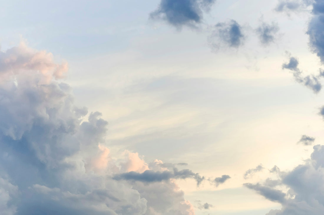 Soft white and grey clouds against a pale yellow sky